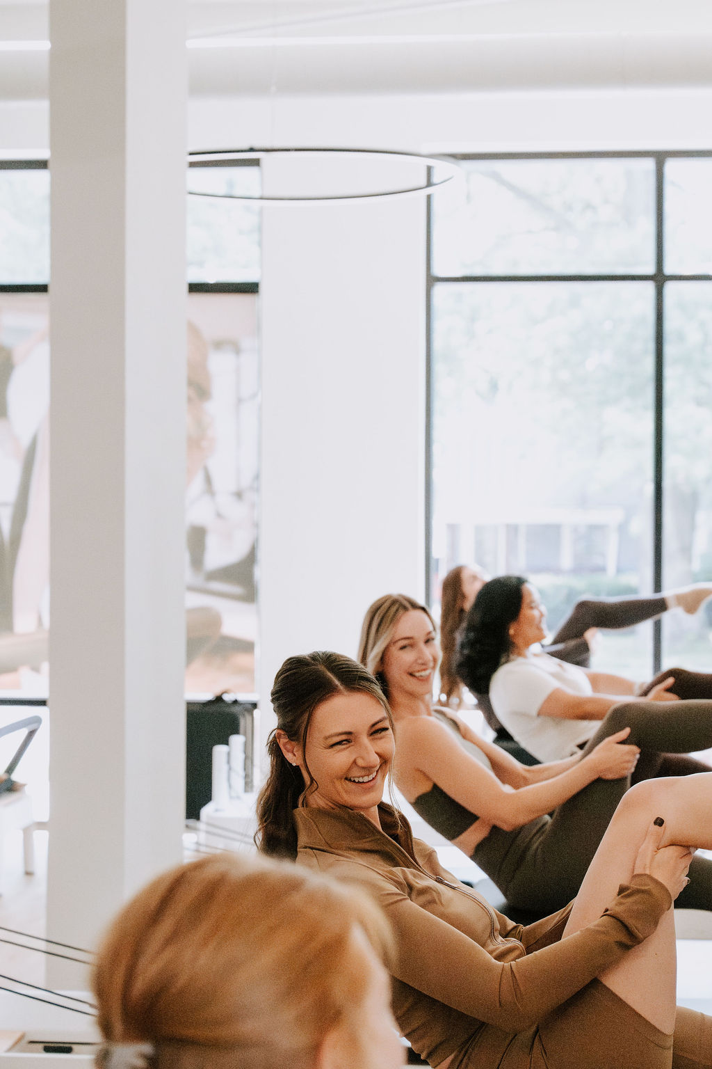 Smiling clients working on Pilates Reformers